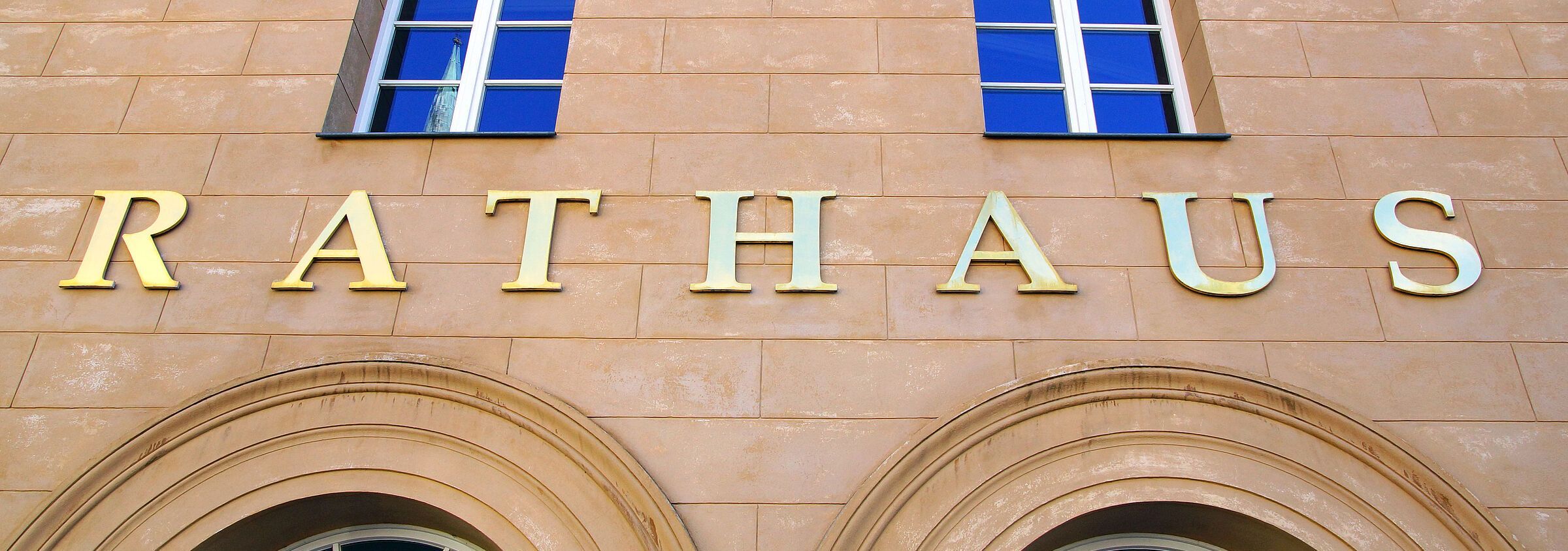 Wählen gehen! Die Kommunalwahlen entscheiden darüber, ob Natur und Umwelt vor Ort auch wirklich geschützt werden. (Foto: DOC-RABE-Media/stock.adobe.com) An einem Gebäude hängt ein goldfarbener Schriftzug "Rathaus"