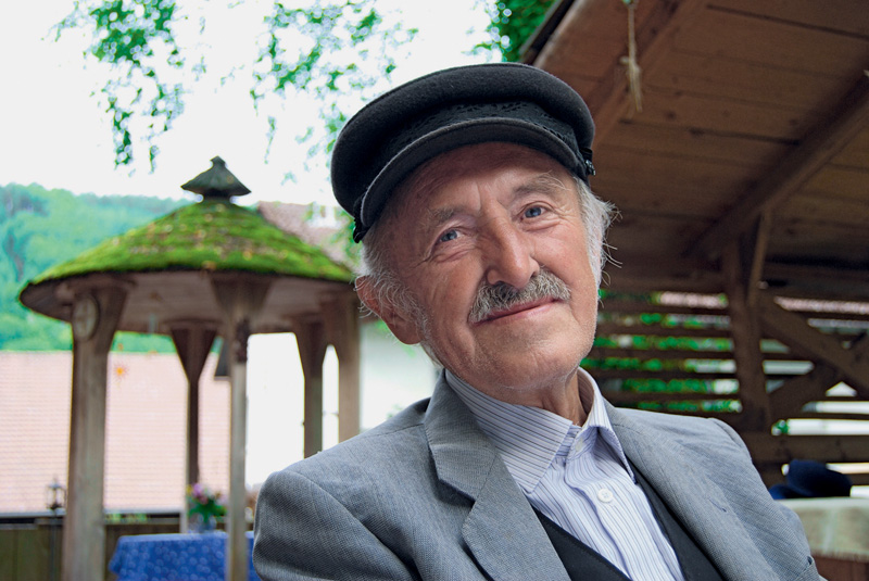 Portrait von Anton Mayer mit einem Hut vor einem Pavillion