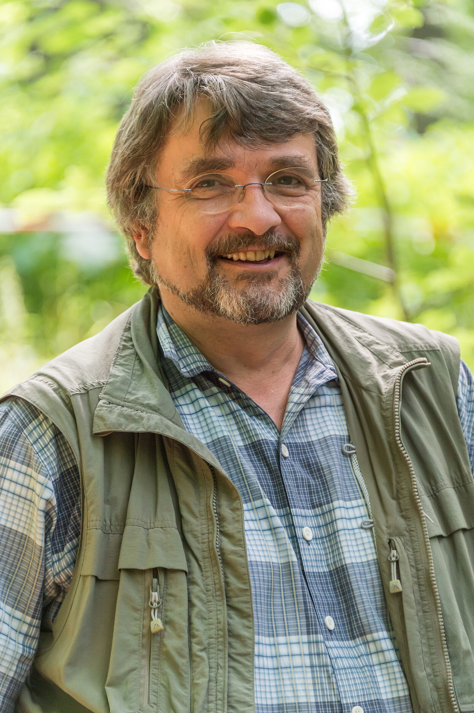 Ein Portrait von Kai Frobel, einem Mann mit grau melierten Haaren, Brille und Bart sowie einem karierten Hemd und beigefarbener Weste. (Foto: Toni Mader)