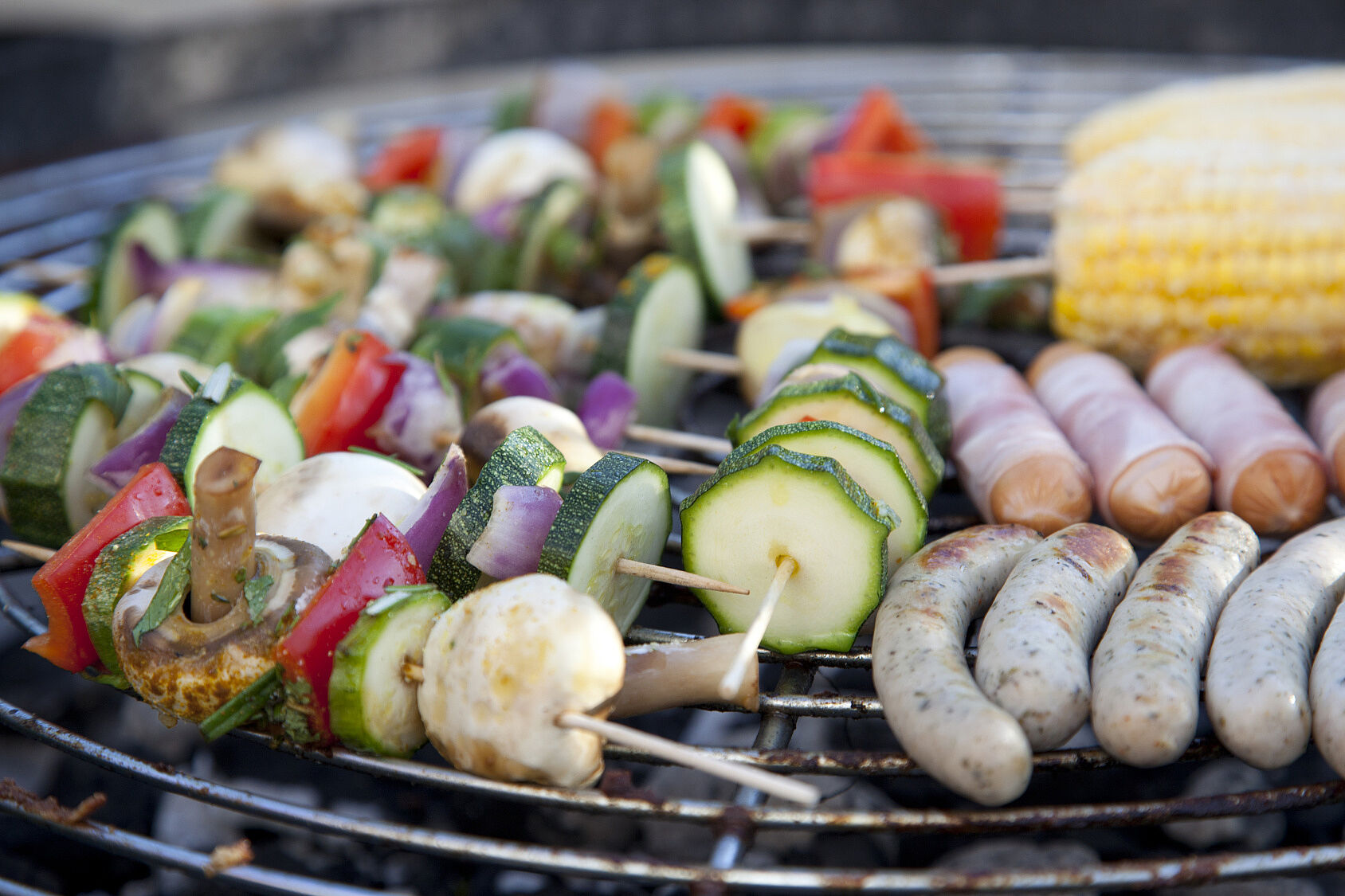 Auf dem Grillrost liegen Gemüsespieße neben Würstchen: Für eine nachhaltige Ernährung müssen wir weniger Fleisch essen. (Foto: Herby Meseri/stock.adobe.com)