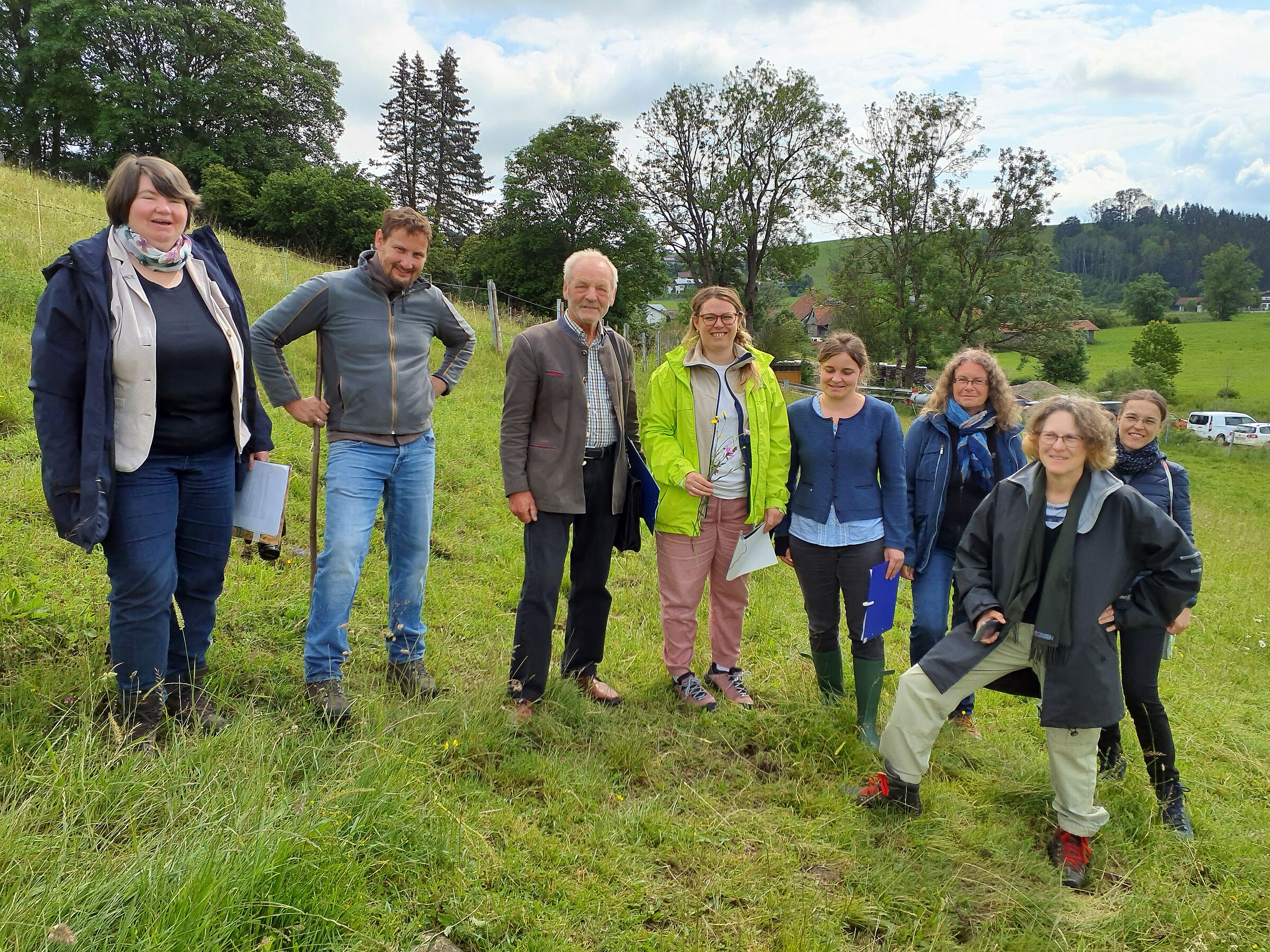 Eine Gruppe von Menschen steht in einer Wiese. Bei der Juryrundfahrt werden die Sieger der Wiesenmeisterschaft festgelegt. (Foto: LfL)