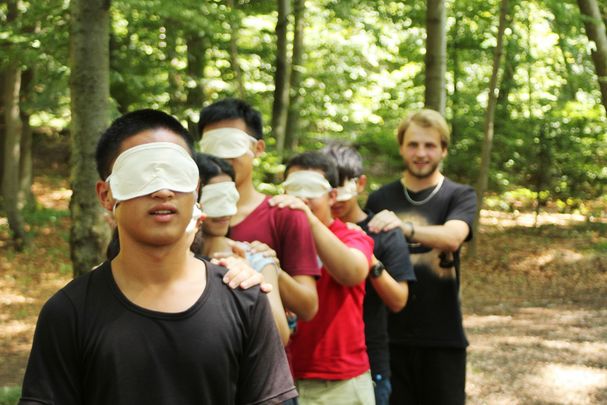 Jugendliche führen sich mit verbundenen Augen durch den Wald (Bild: BN-Archiv)