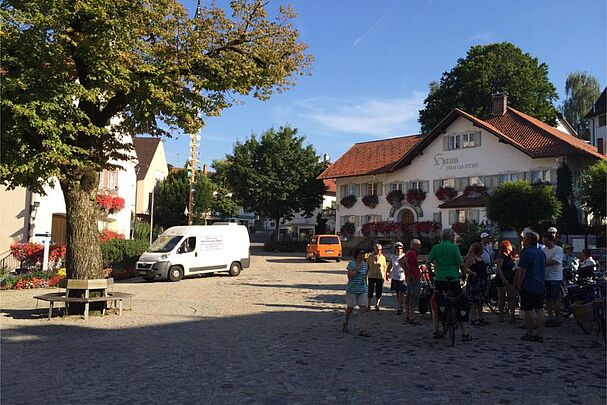 Fußgänger, Rad- und Autofahrer teilen sich den Verkehrsraum in der Ortsmitte von Bad Grönenbach: Rund um die Dorflinde findet sich eine gepflasterte Fläche ohne Begrenzungen – dies hält alle zu Rücksicht an. (Bild: Richard Mergner)