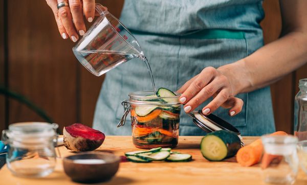 Das Fermentieren ist eine besonders gesunde und nachhaltige Methode, Lebensmittel zu konservieren. (Foto: Microgen/stock.adobecom) Lebensmittel konservieren: Eine Frau gießt Salzlake in ein Glas mit Gemüse.