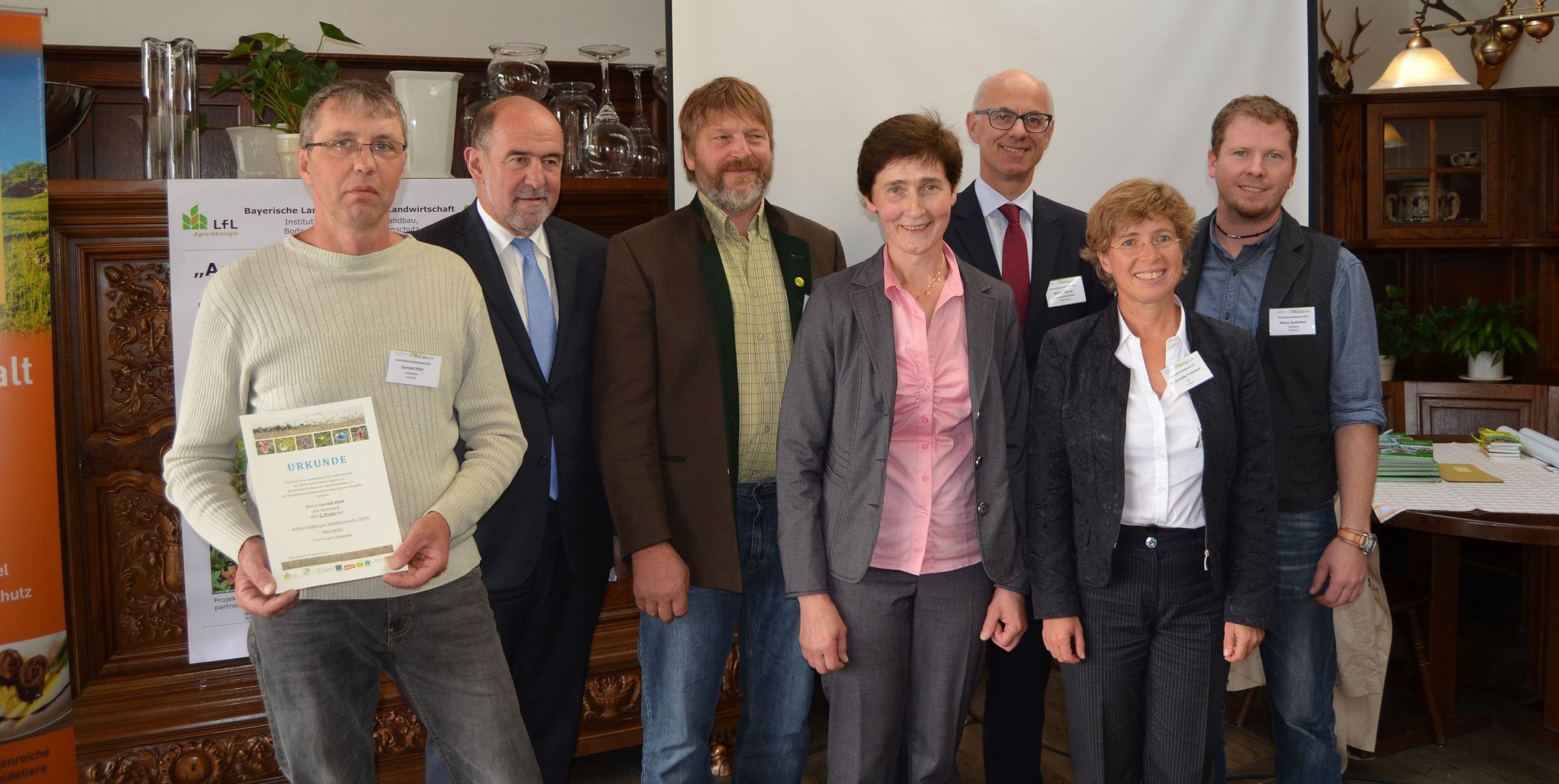 Preisverleihung 2016 Eine Gruppe von sechs Leuten steht in einem Saal. Einer hält eine Urkunde in den Händen. Die Preisverleihung für den Ackerwildkraut-Wettbewerb 2016 fand im September in Regensburg statt. (Tim Fluhrer/BN)