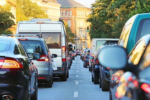 Autos stauen sich zweispurig in langen Schlangen vor einer Ampel: Der wachsende Autoverkehr fordert immer mehr Platz und führt zu wachsenden Luft-, Lärm- und Umweltproblemen. (Bild: Adobestock/Kara)